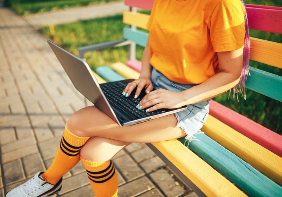 young-beautiful-girl-holding-a-laptop-in-a-yellow-t-shirt-sitting-on-a-bench-in-the-open-air-woman_t20_G0RPm1